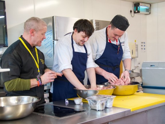 Richard Punshon showing two catering students how to make venison salami and chorizo.