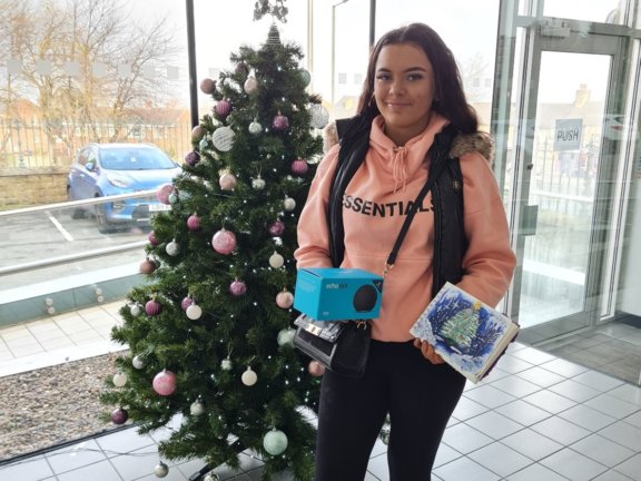 student holding book with drawing in in front of Christmas tree