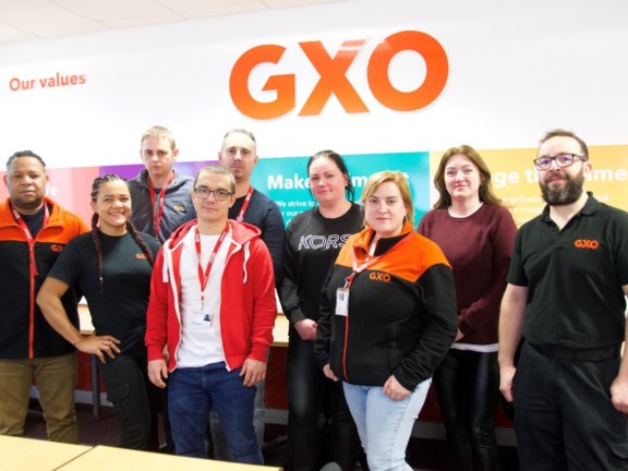 group of people stood in front of GXO logo