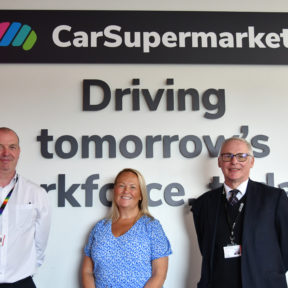 Three people stood in front of a white wall with Car Supermarket logo and the words "Driving tomorrow's workforce today."