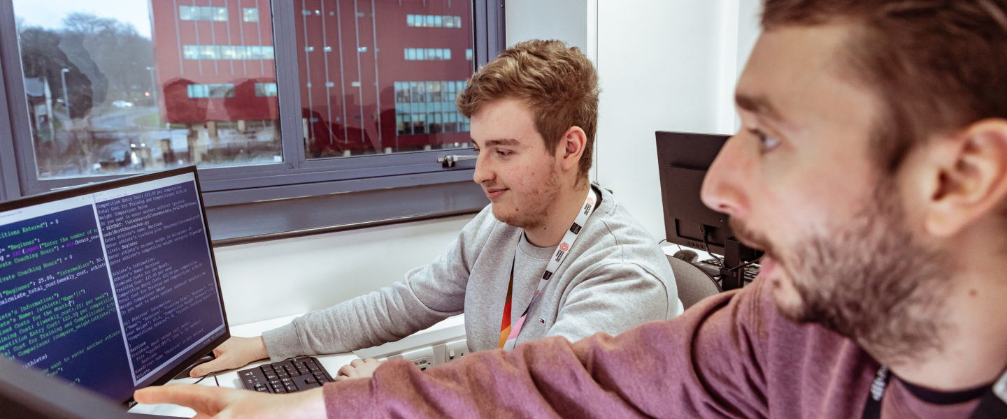 Two people sat pointing at a computer screen.