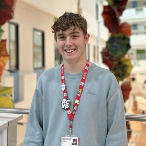 brown haired student with long sleeved blue shirt and red student lanyard