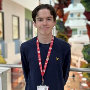 dark haired student wearing navy long sleeve shirt with red student lanyard