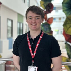 brown haired student wearing black polo shirt with red student lanyard