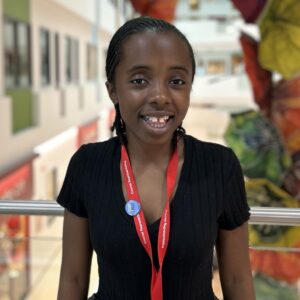 student with braided black hair wearing black shirt and red student lanyard