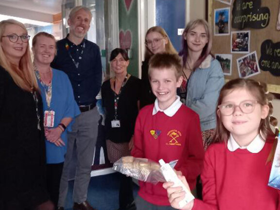 Staff and students smiling at the camera holding donations of food.